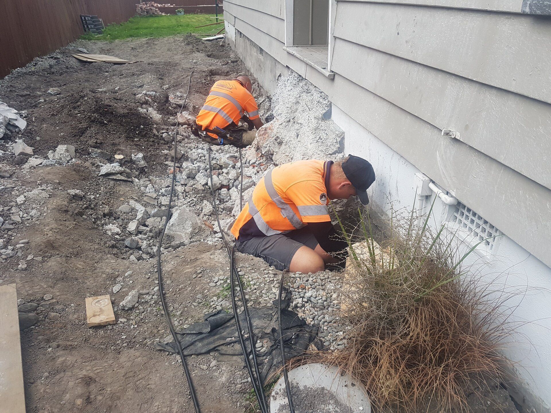 Two men are working on the side of a house.