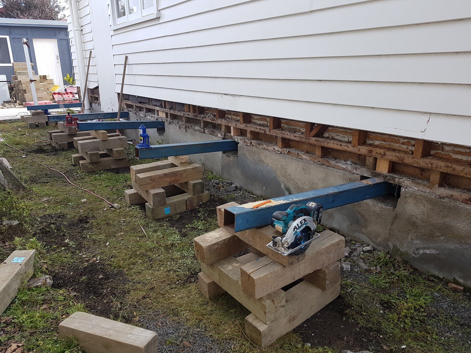 A machine is sitting on a wooden block next to a house.