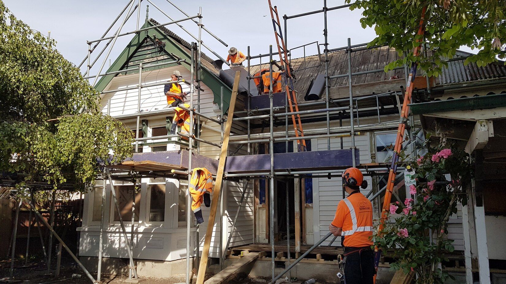 A group of construction workers are working on the roof of a house.