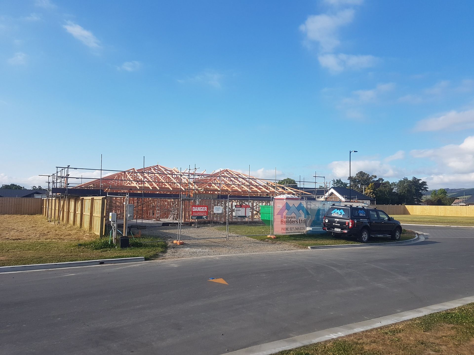 A car is parked in front of a building under construction.