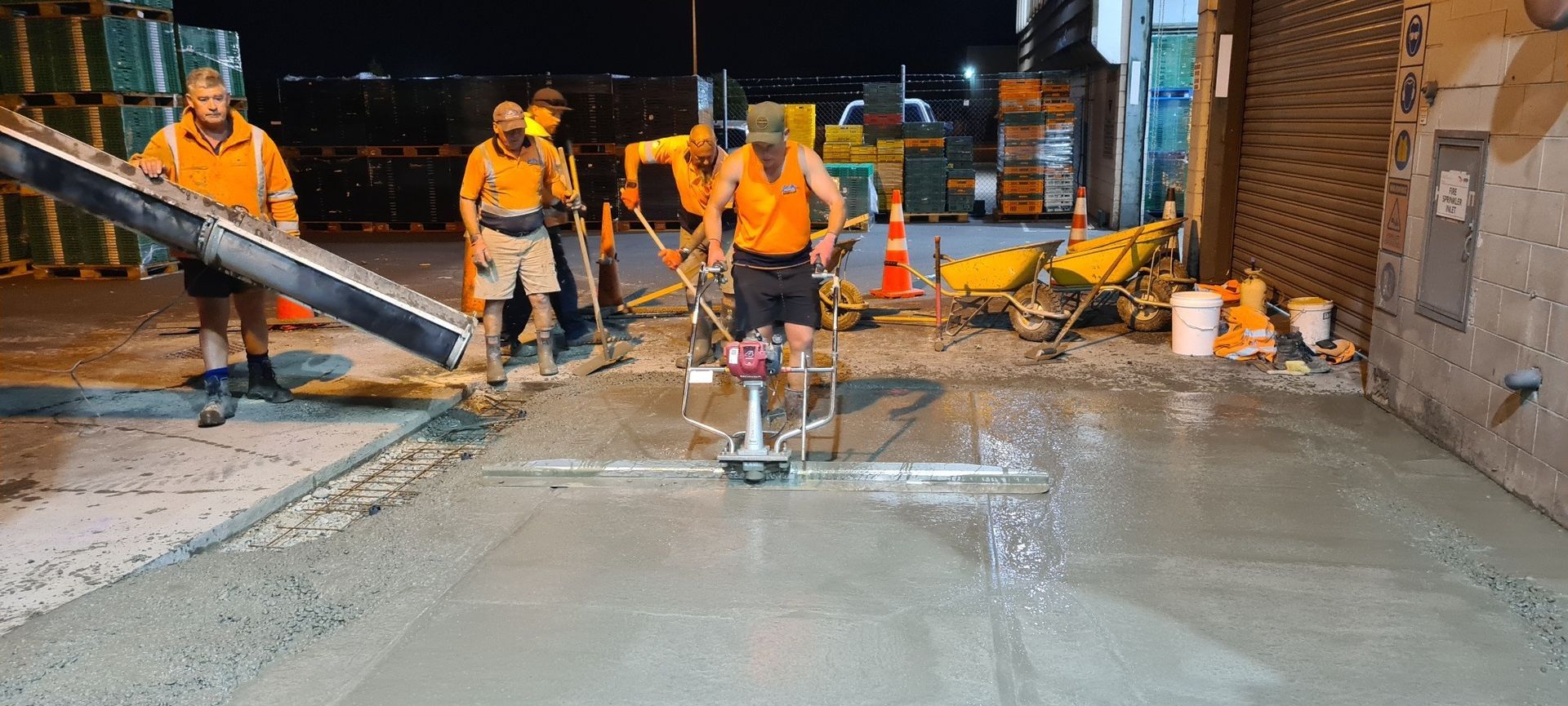 A group of construction workers are working on a concrete floor.