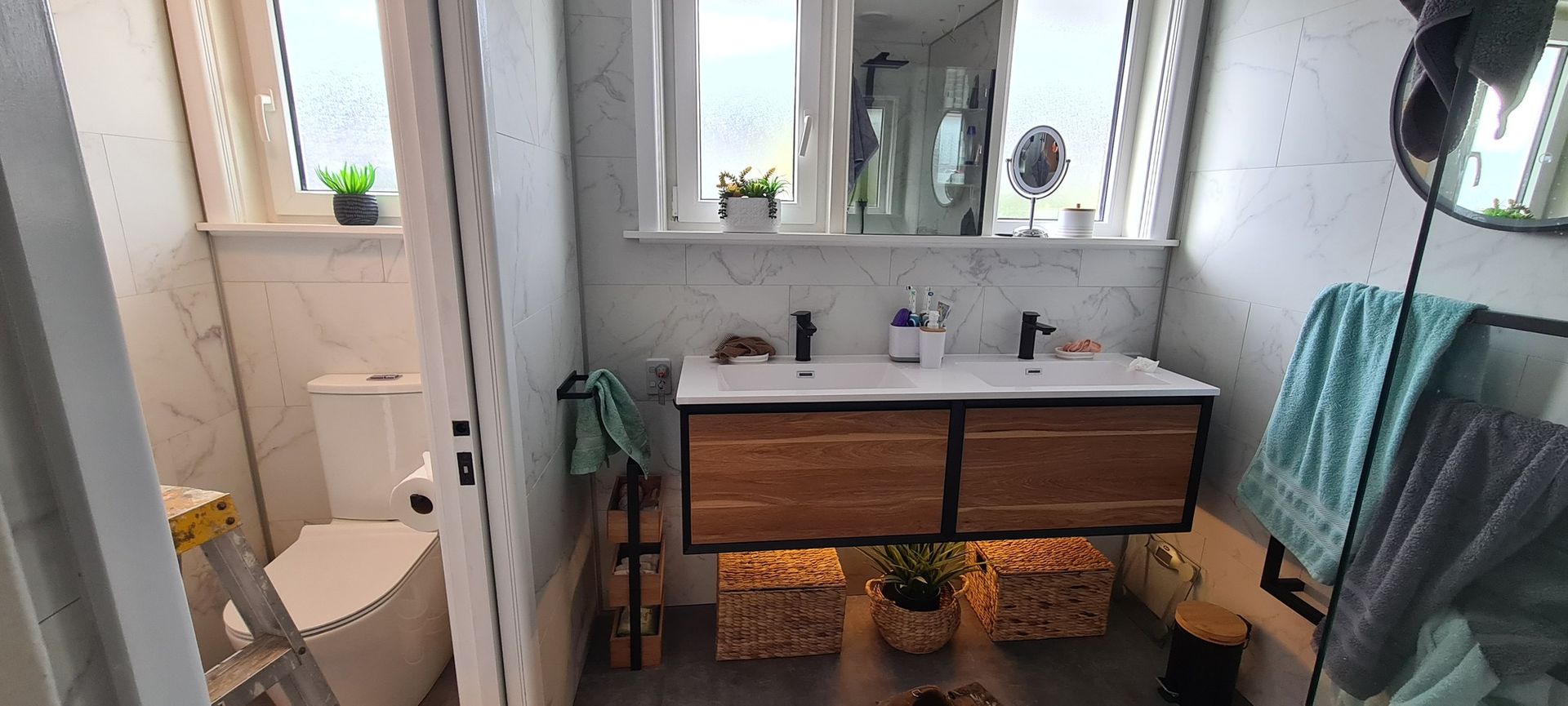 A bathroom with two sinks , a toilet , and a mirror.