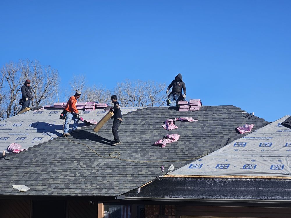 Roofers replacing shingles on a house on a sunny day.