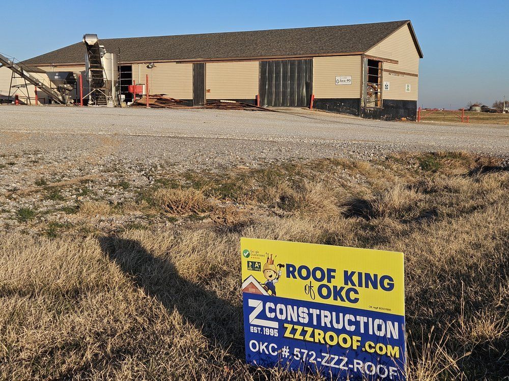 Sign for Z Construction in front of a tan building with a gravel driveway and brown grass.