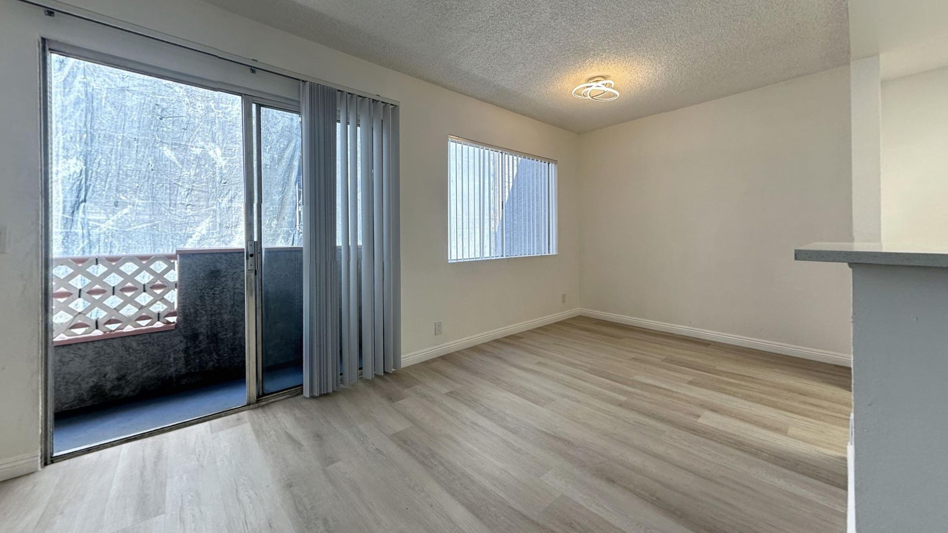 Empty living room with sliding glass door leading to a small balcony, and a window.
