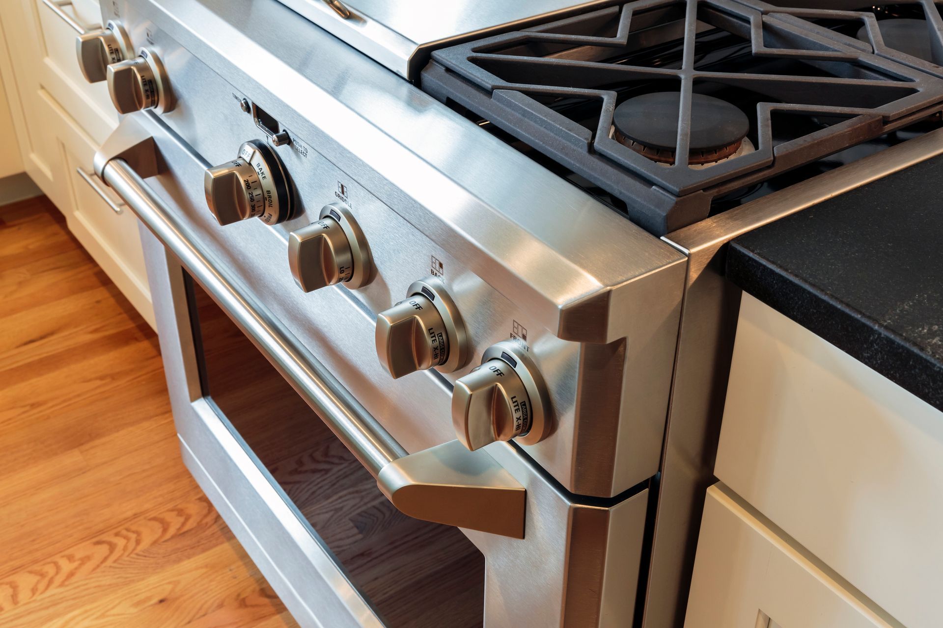 Stainless steel gas range in kitchen with knobs and oven door.
