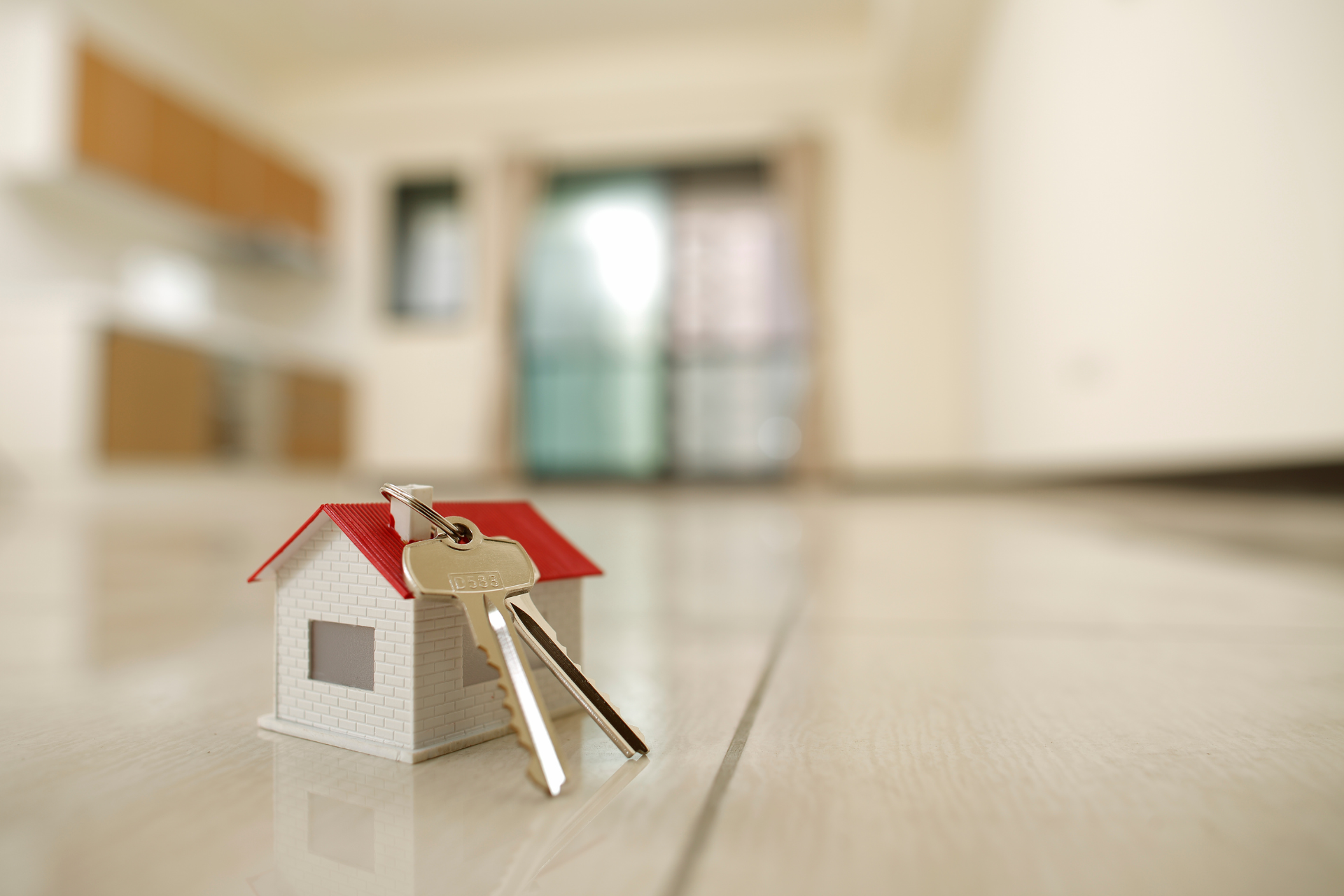 A small house with keys on the floor in an empty room.