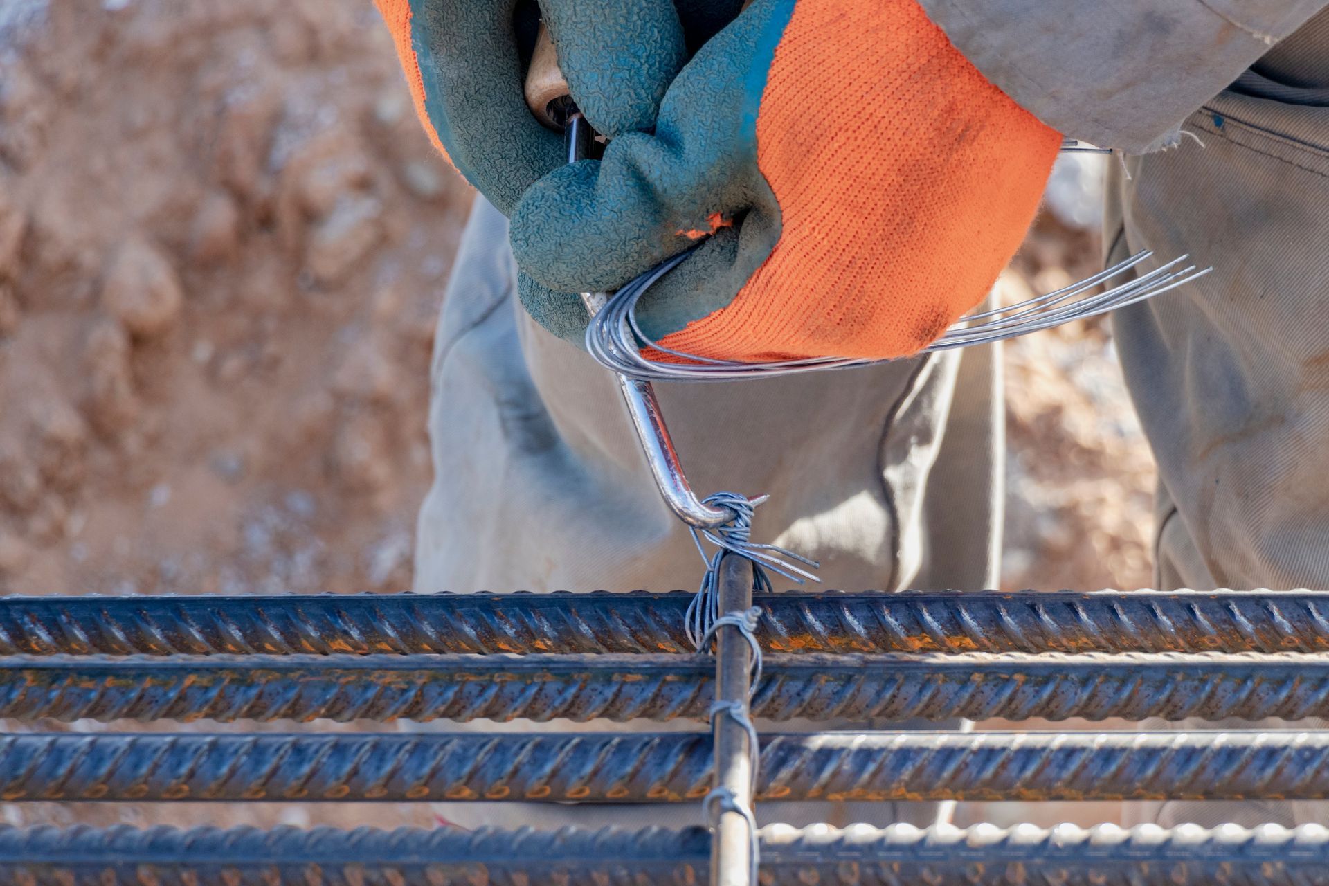 A worker is using tie wire to reinforce bars in a construction site. A worker is using tie wire to reinforce bars in a construction site.