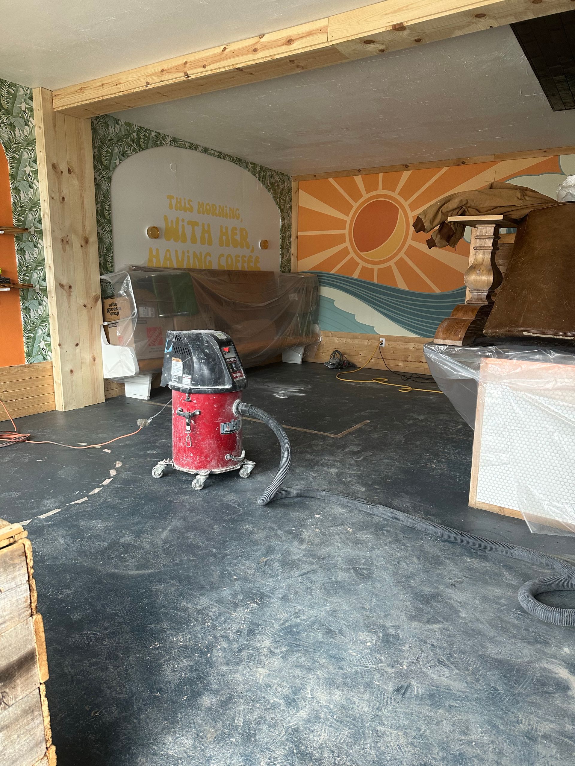 A vacuum cleaner is sitting on the floor in a room with a mural on the wall.