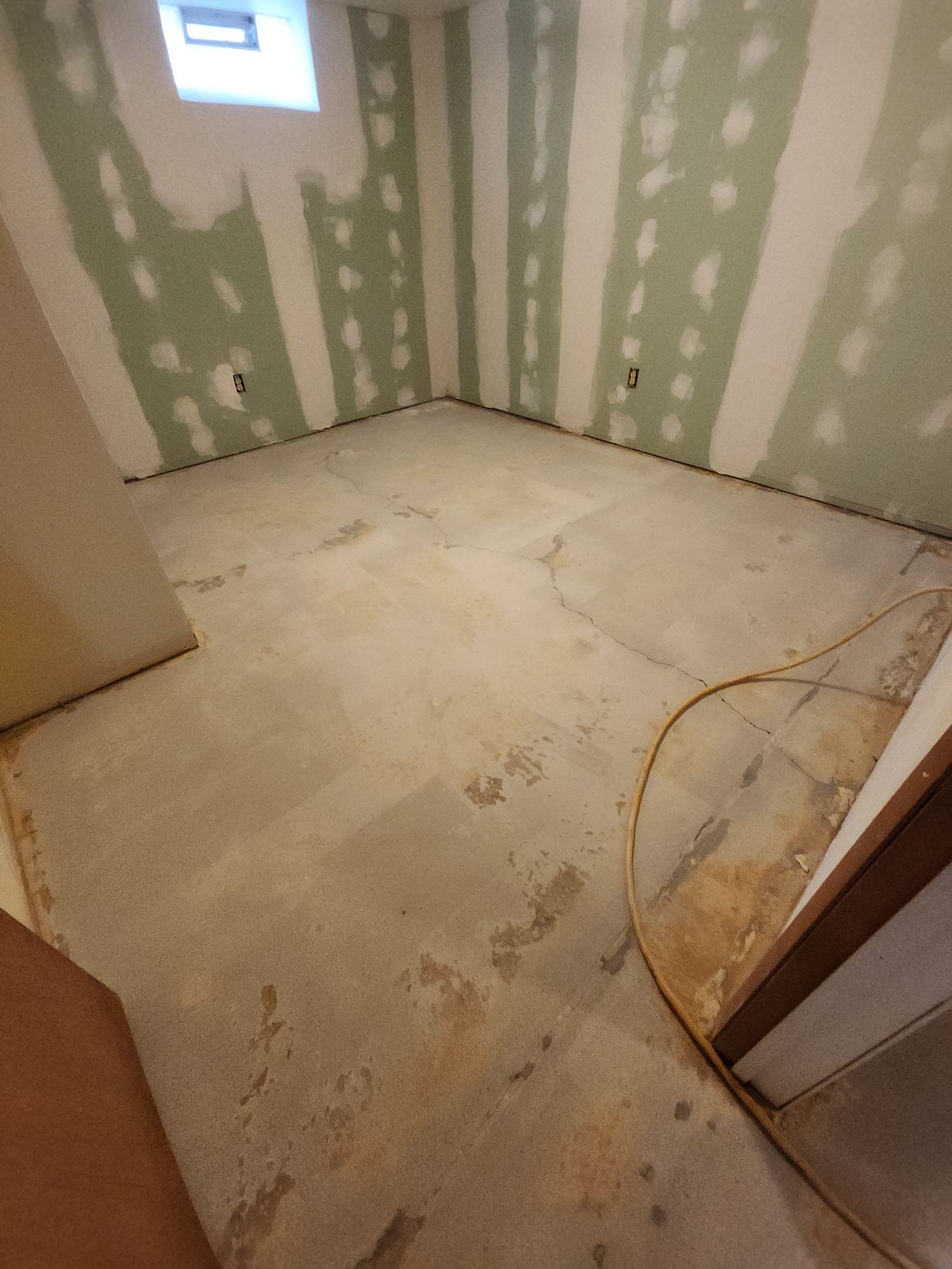 A room with a concrete floor and green walls is being remodeled.