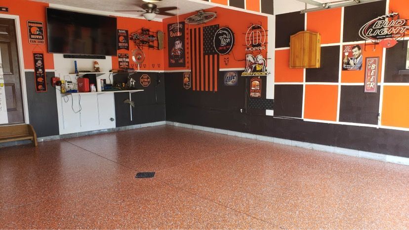 An empty garage with orange and black walls and a flat screen tv.