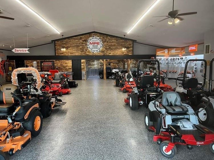 A large room filled with lawn mowers and a ceiling fan.