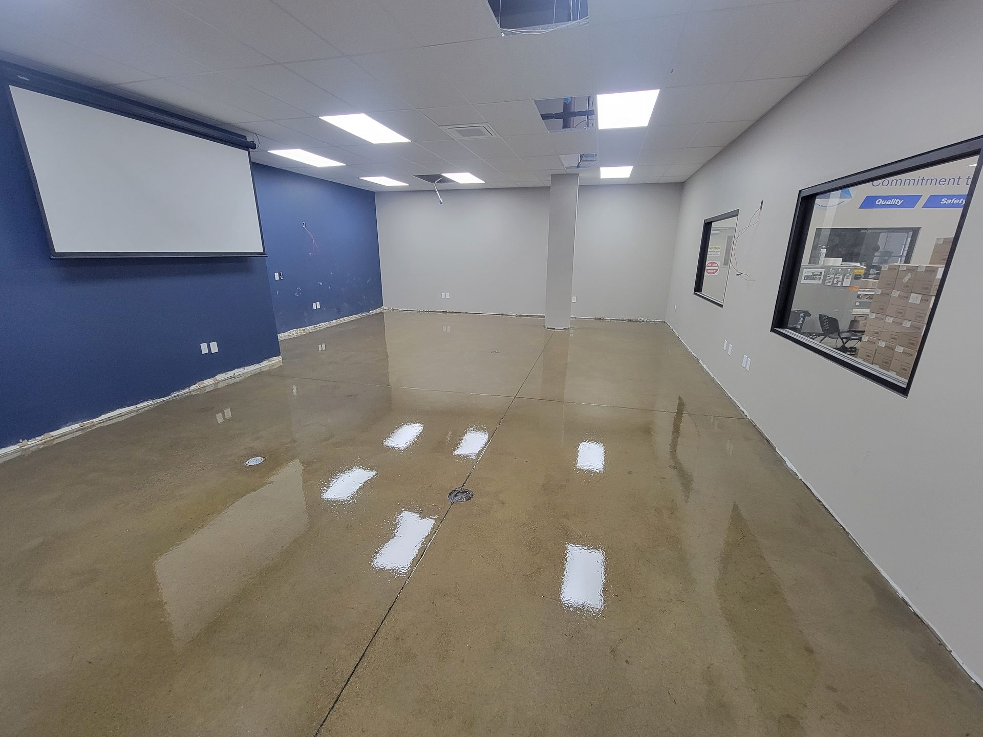 A large empty room with a projector screen on the wall.