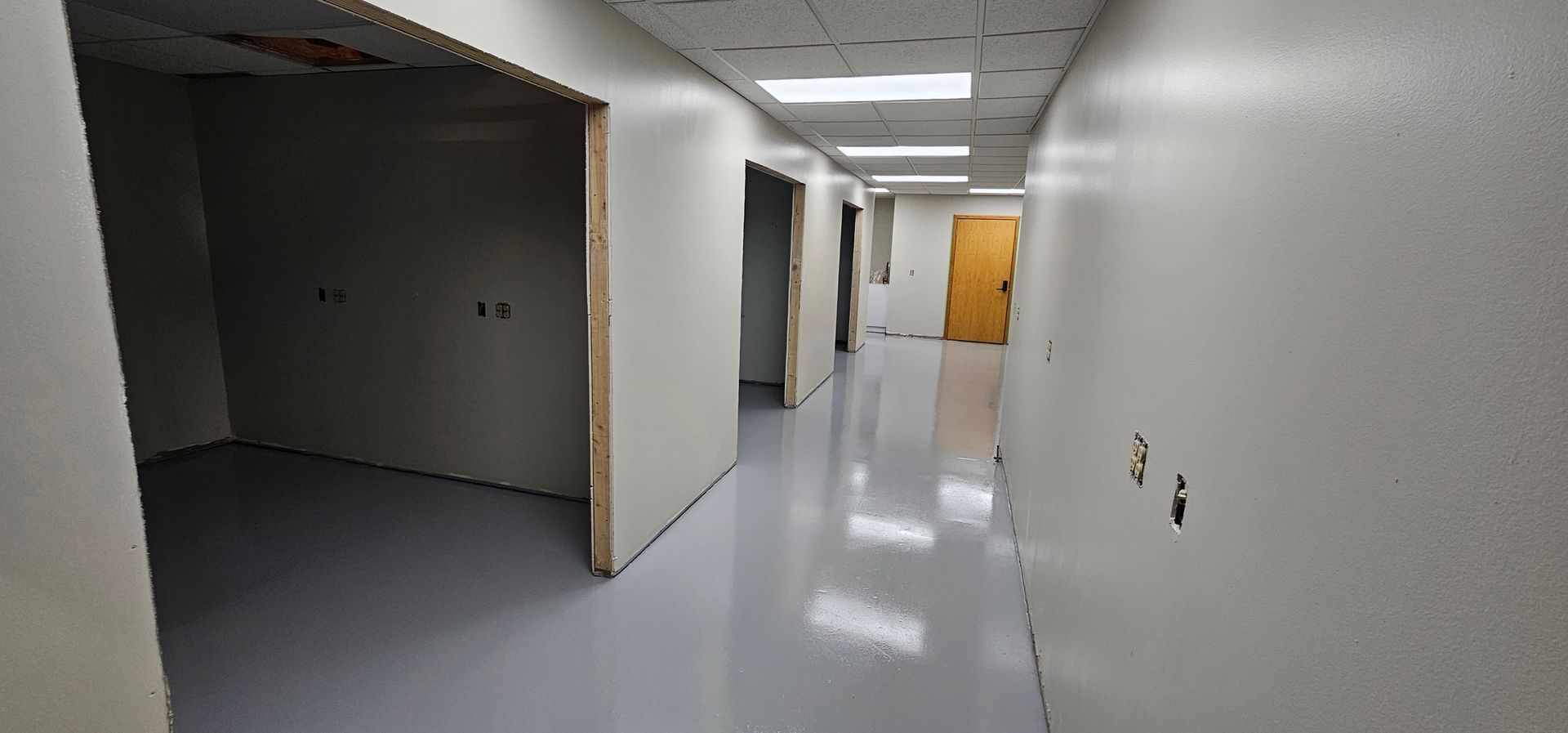 A long hallway with white walls and a yellow door.