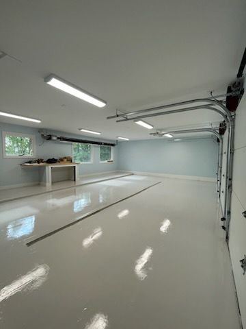 A large empty garage with a white floor and a garage door open.