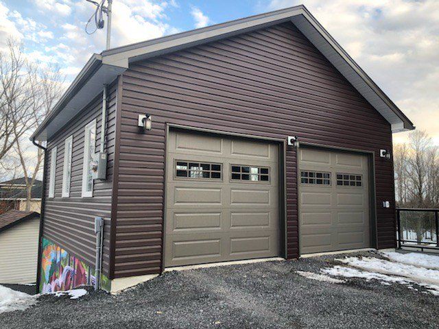 A brown garage with two garage doors and a roof