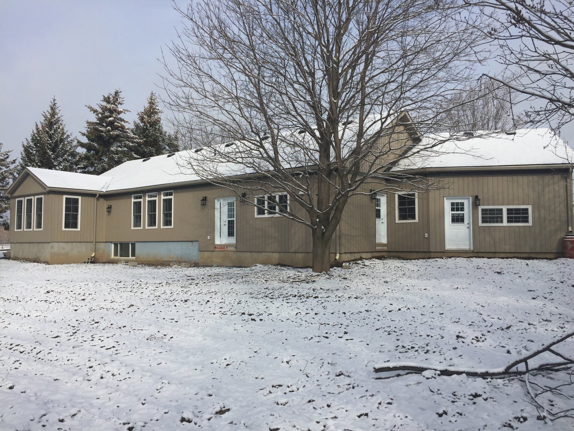 A house with a lot of windows is covered in snow