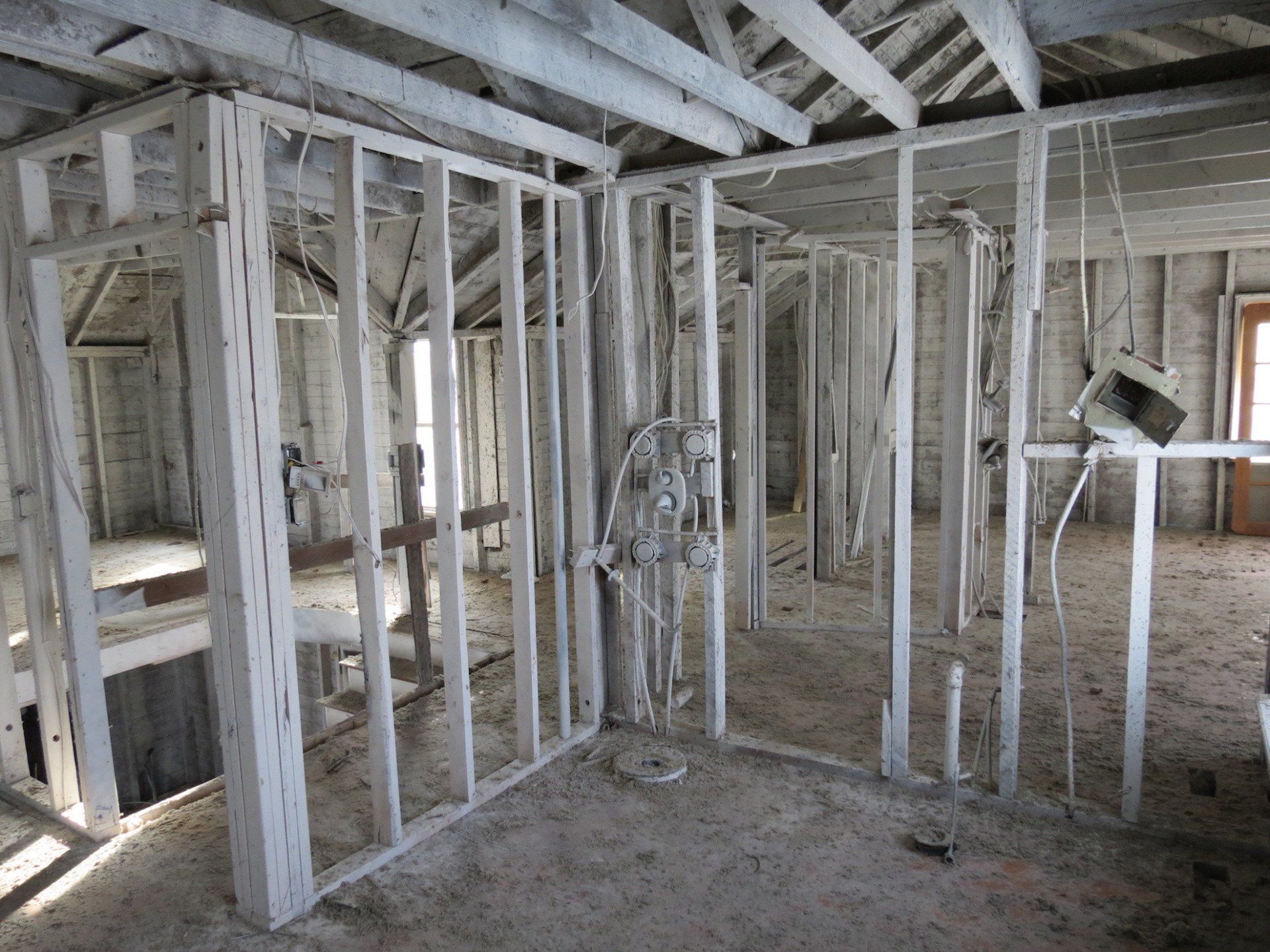 A room with a lot of wooden beams and a lot of wires hanging from the ceiling.