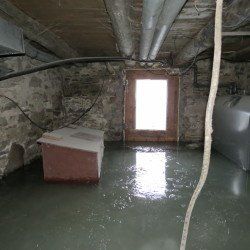 A flooded basement with a window and a tank.