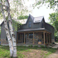 A large house with a porch and a tree in front of it.
