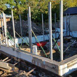 A building under construction with a wheelbarrow in the foreground.