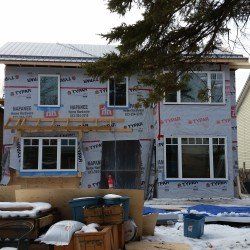 A house is being built in the snow with a lot of windows.