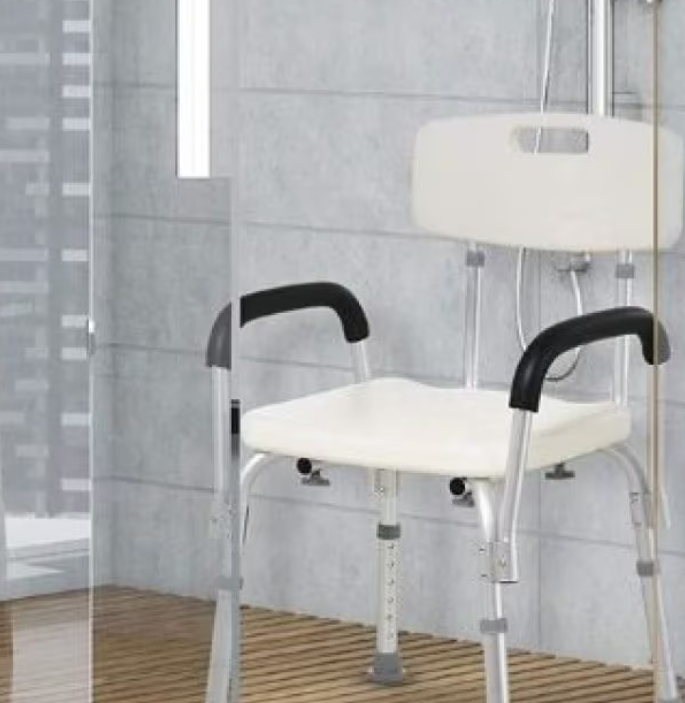 Una sedia da doccia bianca con braccioli imbottiti neri e struttura metallica regolabile, posizionata all'interno di un box doccia piastrellato.