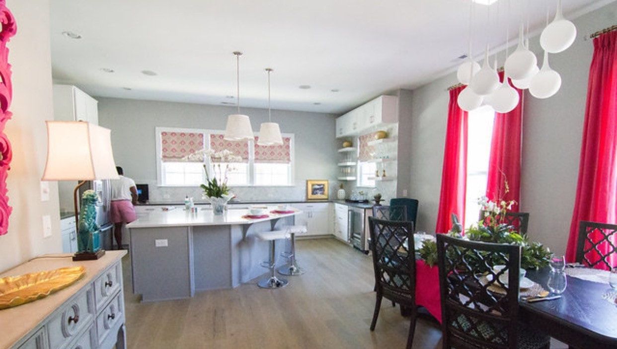 A kitchen and dining room in a house with pink curtains.