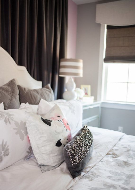 A bedroom with a bed , pillows , a lamp and a window.