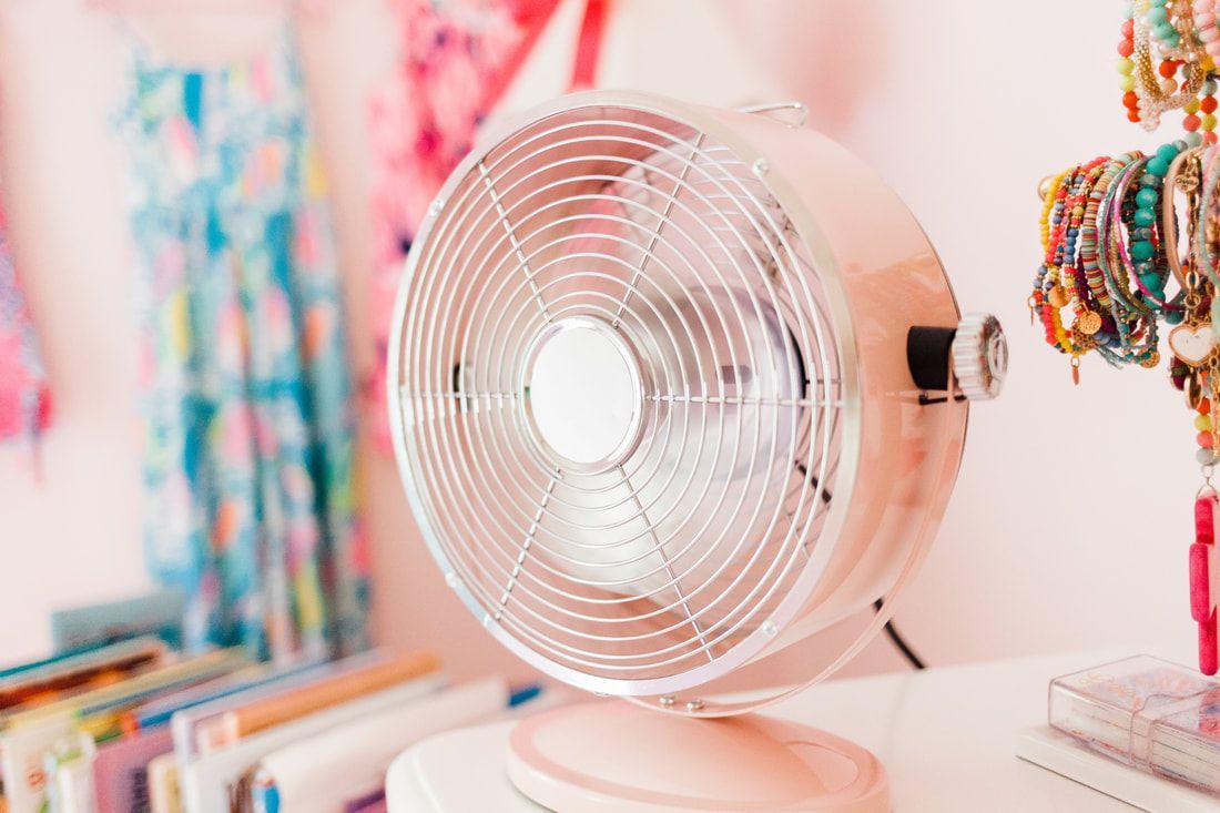 A pink fan is sitting on a table in a room.