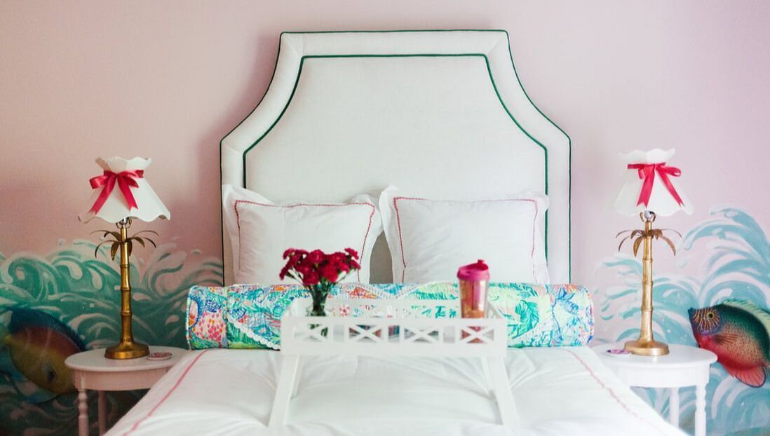 A bed with a white headboard and a white tray on it.