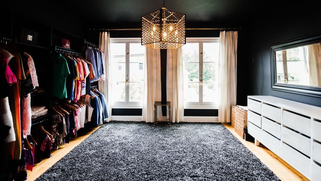 A large walk in closet filled with lots of clothes and a chandelier.