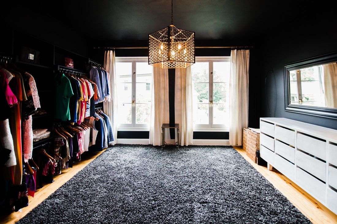 A large walk in closet filled with lots of clothes and a rug.