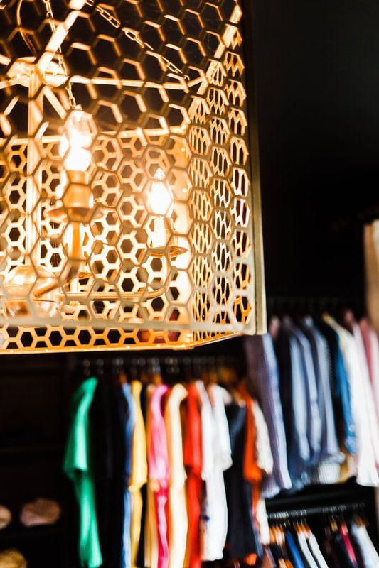 A closet filled with clothes and a lamp hanging from the ceiling.
