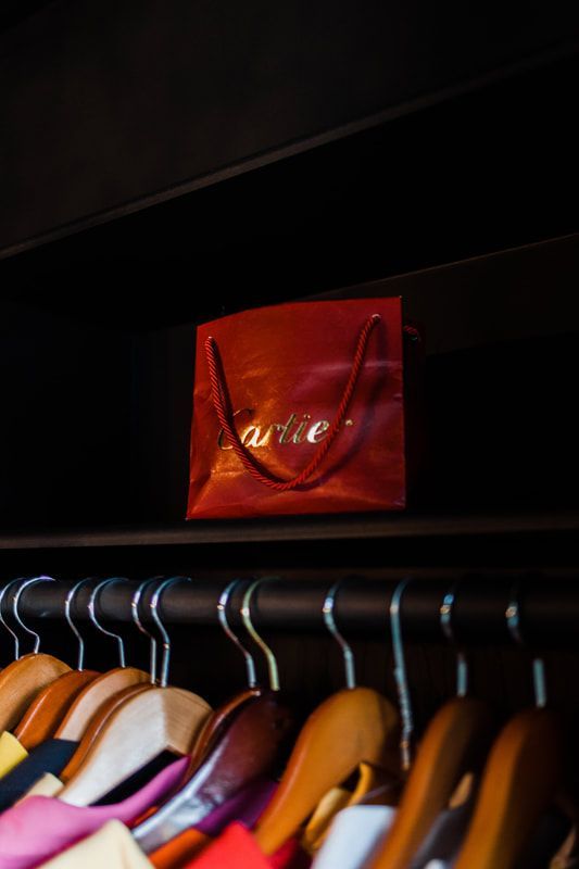 A red cartier bag hangs above a row of clothes