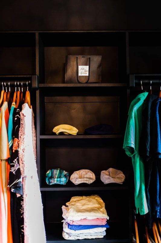 A closet filled with clothes and a bag on the shelf.