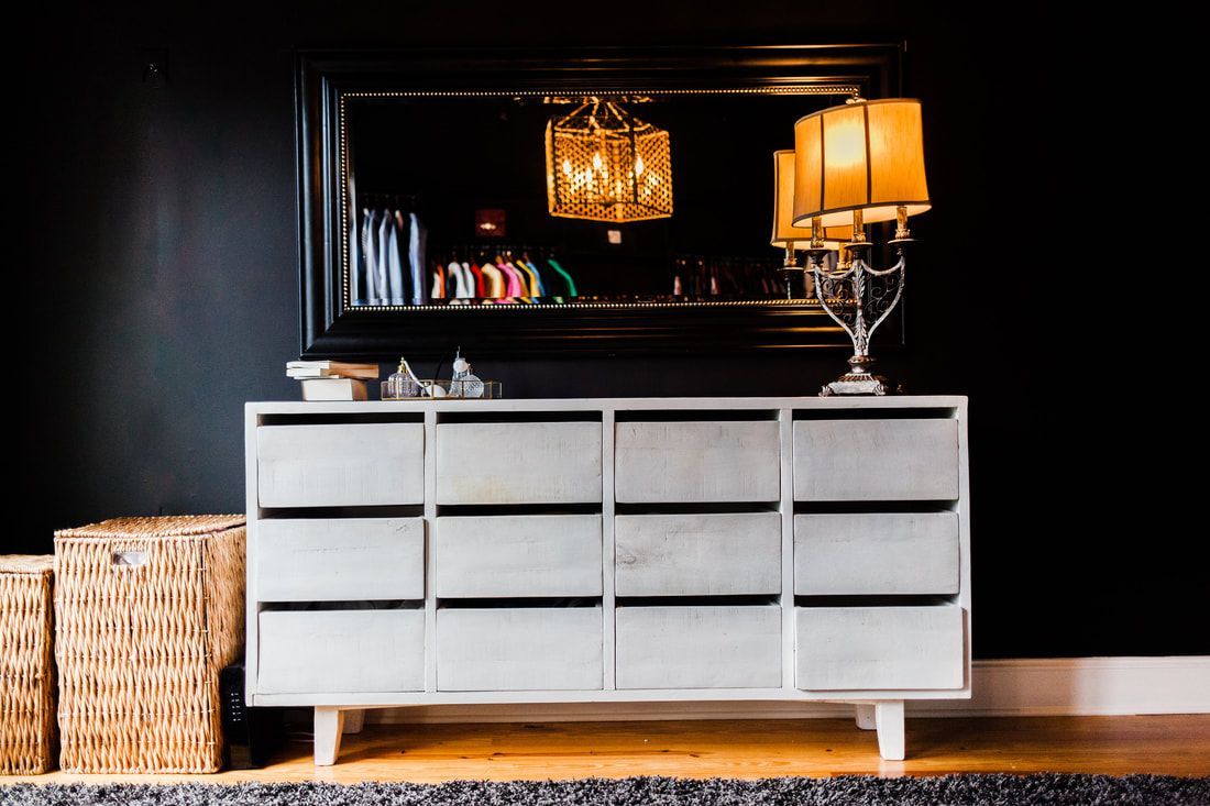A dresser with a lamp and a mirror in a living room.