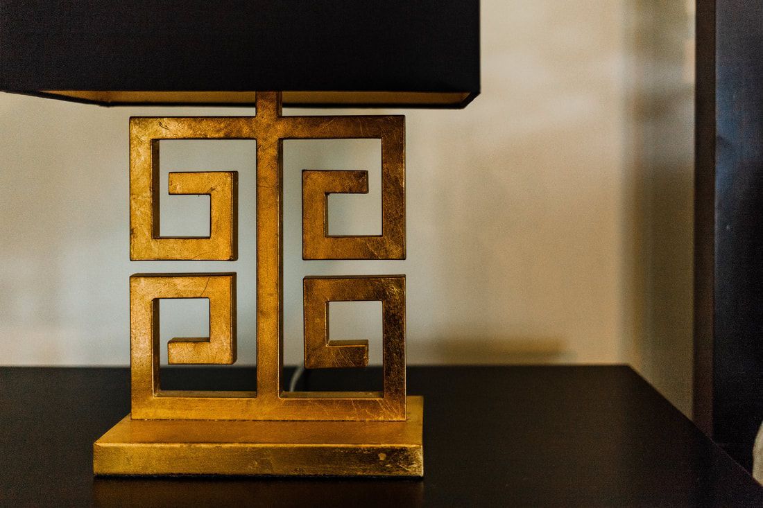 A gold lamp with a black shade is sitting on a table.