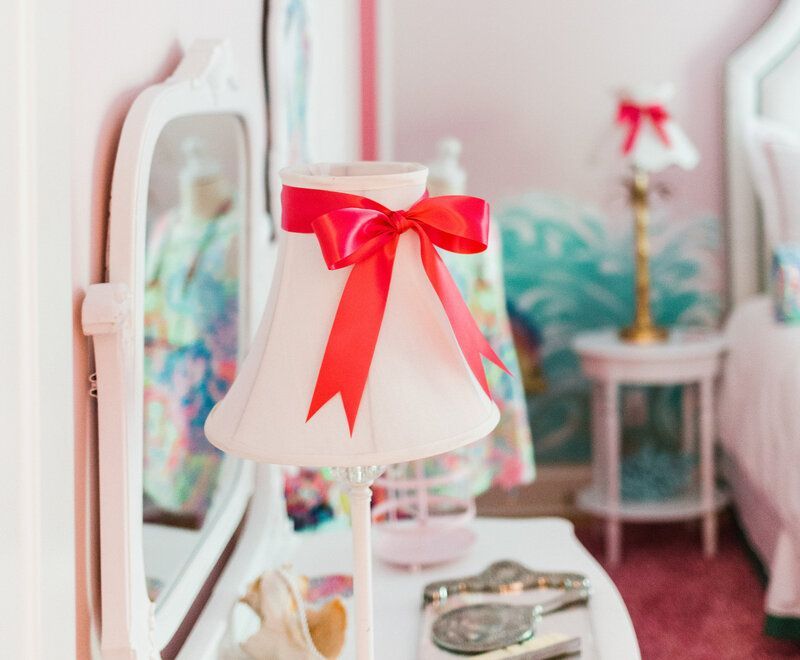 A lamp with a red bow on it is sitting on a table in front of a mirror.