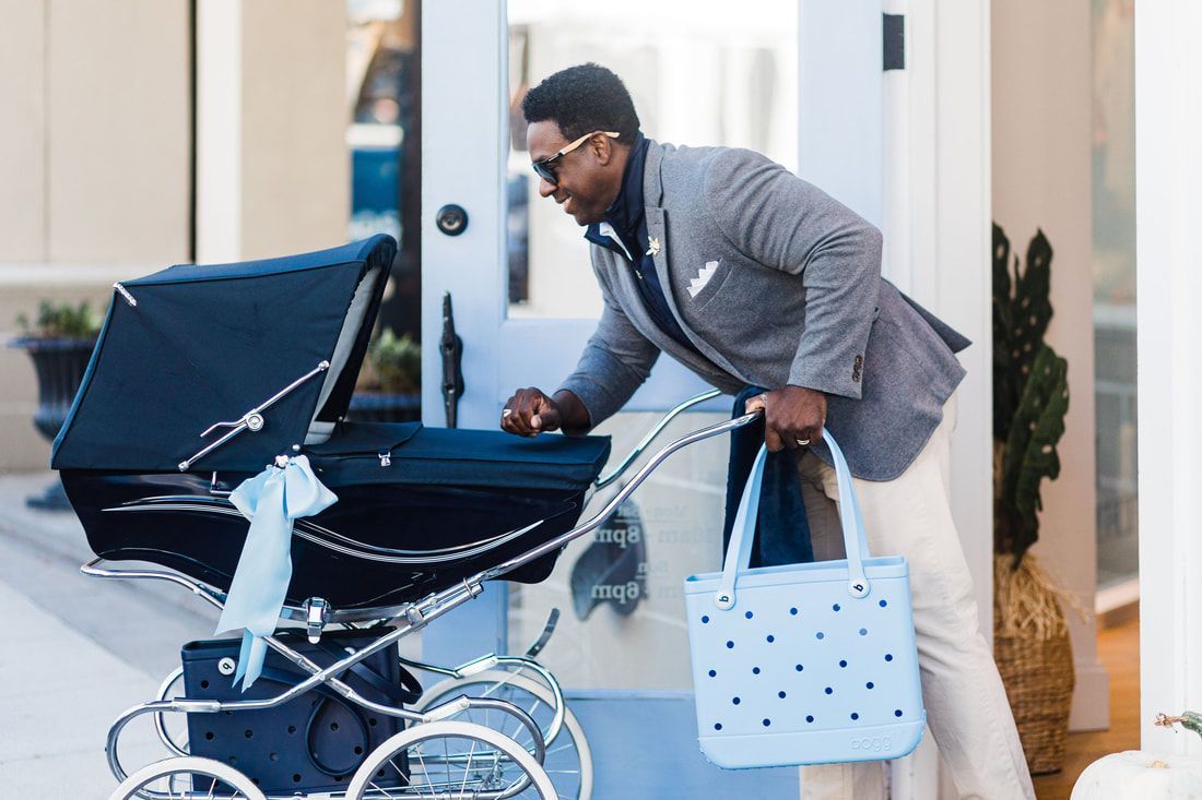 A man is pushing a blue stroller with a blue bag.