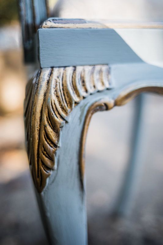 A close up of a chair 's leg with a gold carving on it.