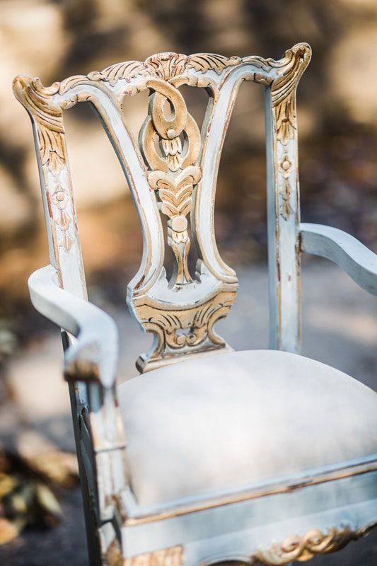 A white and gold chair with a white cushion is sitting on the ground.