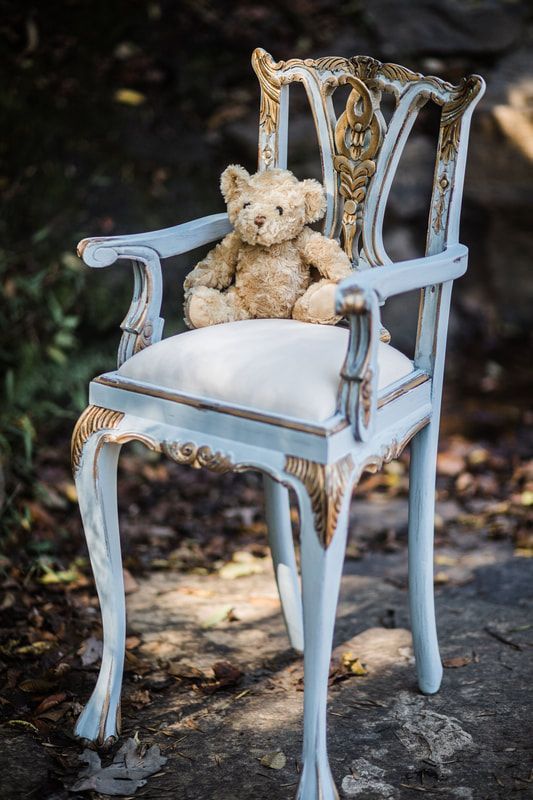A teddy bear is sitting on a blue chair.