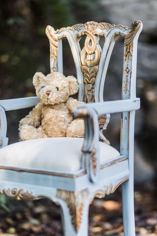 A teddy bear is sitting on a blue chair.