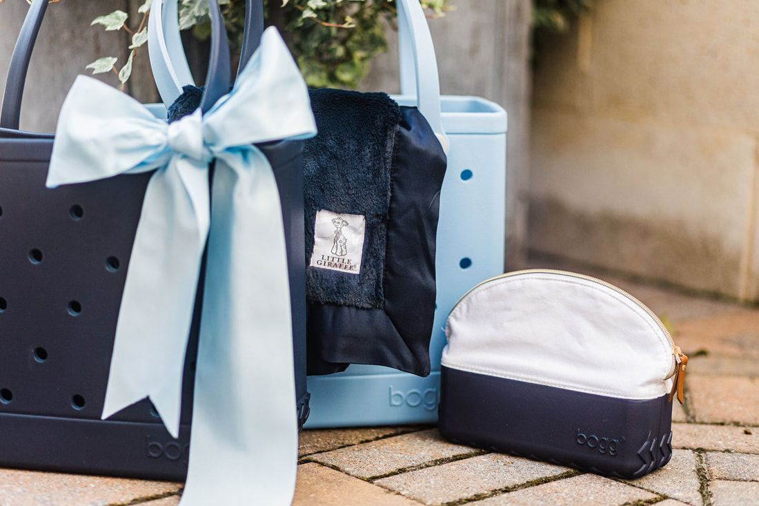 A blue bag with a bow on it is sitting on a brick floor next to a purse.