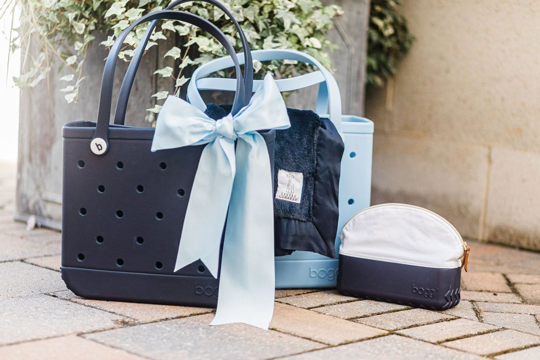 A black bag with a blue bow is sitting on a brick sidewalk next to a blue bag.