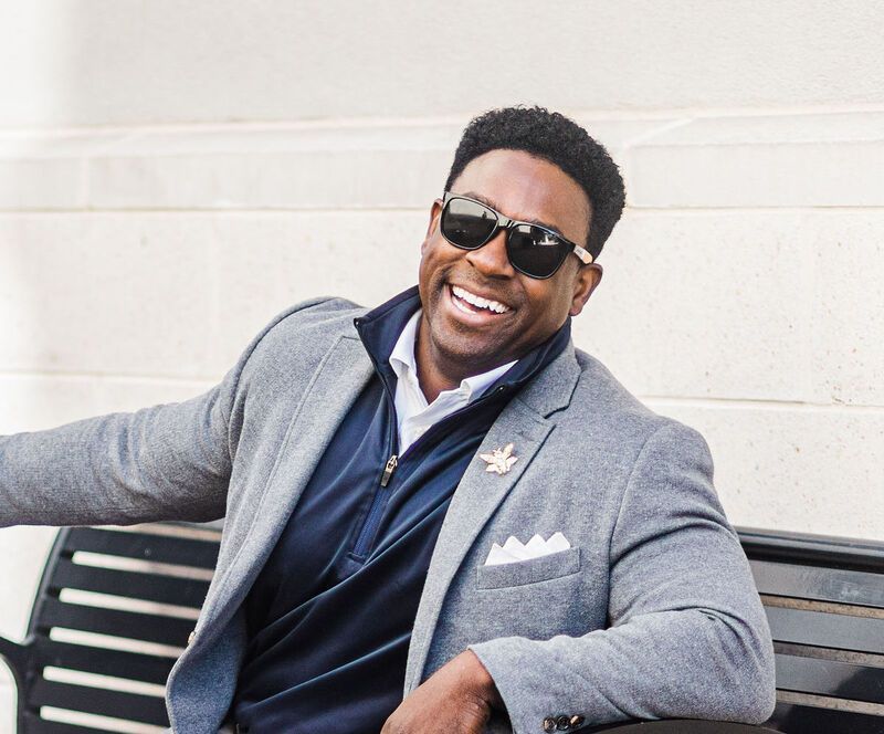 A man in a suit and sunglasses is sitting on a bench