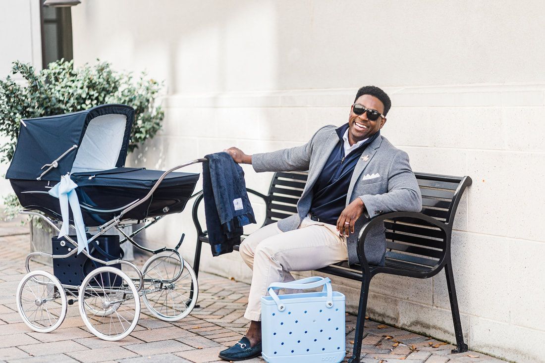 A man is sitting on a bench next to a stroller.