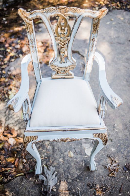 A white and gold chair is sitting on a rock.