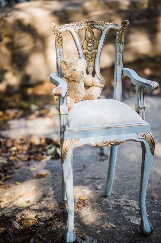 A teddy bear is sitting on a white chair.